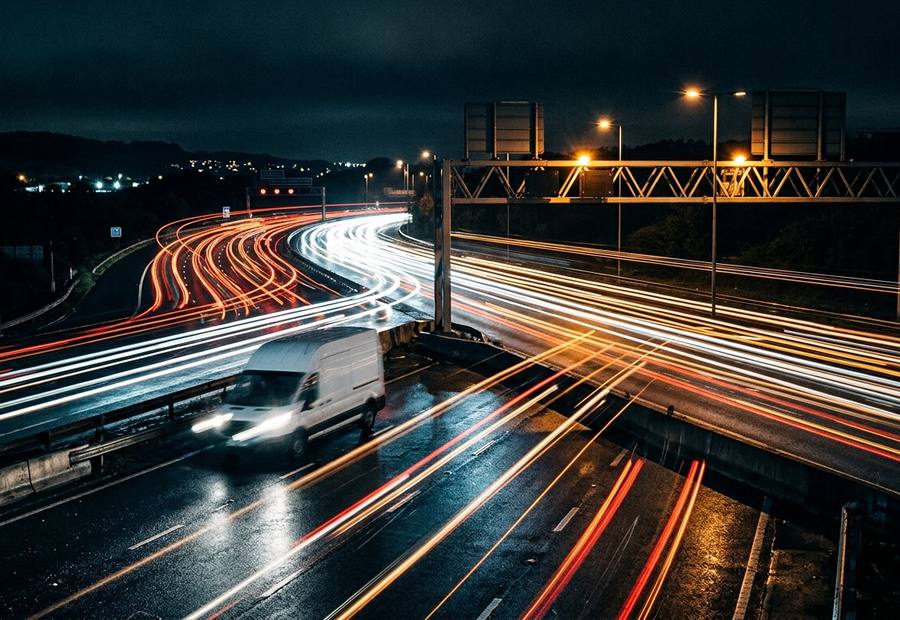 White delivery van on a UK motorway at night with light trails for overnight express shipping